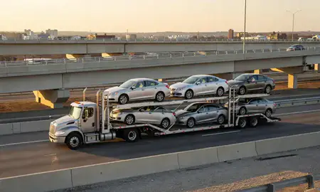Car transporter with the Warwick, Rhode Island, United States skyline behind it