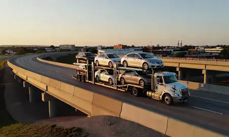 Car transporter with the Hartford, South Dakota, United States skyline behind it