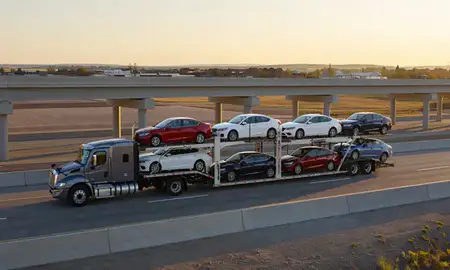 Car transporter with the Tea, South Dakota, United States skyline behind it