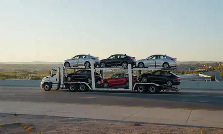 Car transporter with the Millcreek, Utah, United States skyline behind it