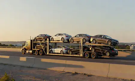Car transporter with the Derby Line, Vermont, United States skyline behind it