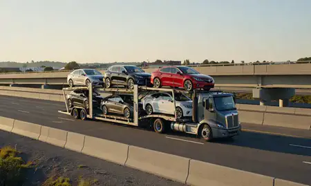 Car transporter with the Essex Junction, Vermont, United States skyline behind it