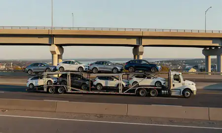 Car transporter with the Newport, Vermont, United States skyline behind it