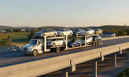 Car transporter with the North Bennington, Vermont, United States skyline behind it