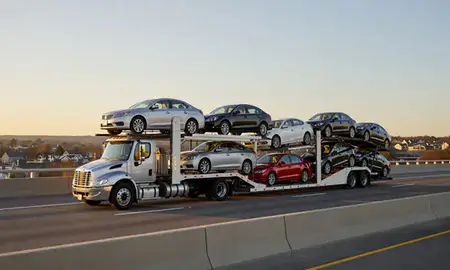 Car transporter with the Linton Hall, Virginia, United States skyline behind it