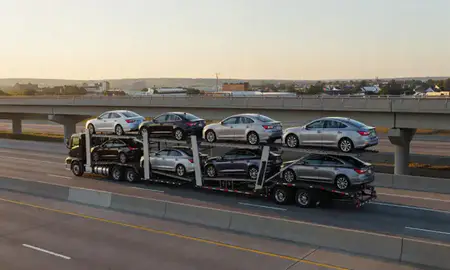 Car transporter with the Greenfield, Wisconsin, United States skyline behind it