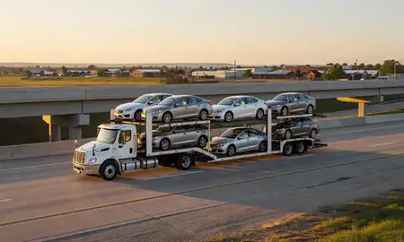 Car transporter with the Sun Prairie, Wisconsin, United States skyline behind it